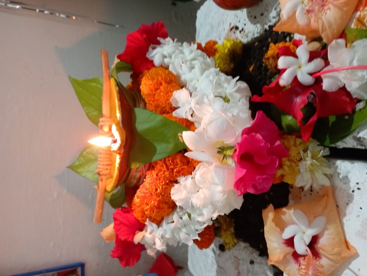 A decorated kalash with diya and fresh flowers used in puja